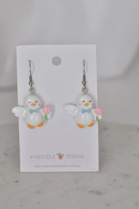 White resin duck drop earrings with blue bow tie and pink tulip, on Kaboodle Designs card