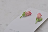 Close-up angled view of tulip stud earrings showing resin texture and stem detail