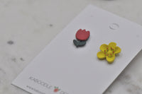 Close-up angled view of tulip and yellow flower resin stud earrings