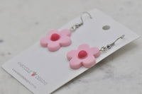 Close-up angled view of pink flower resin earrings showing hook and jump ring detail