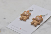 Close-up of bear earrings lying flat showing tan resin finish and paw detail