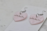 Close-up of pink heart earrings showing heartbeat print and silver hook detail