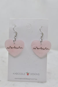 Pair of pink Perspex heart drop earrings with heartbeat line design on card