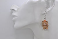 Bear earring with peach hat shown on ear for scale
