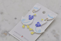 Silly Goose earrings laid flat showing gold jump ring and blue bow detail