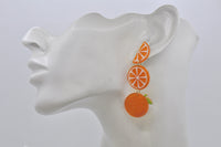 Orange fruit earrings shown on ear model for scale