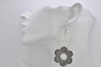 Skull and flower drop earring shown worn on ear, side view against plain background