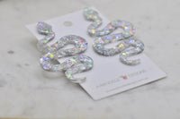 Close-up of holographic glitter snake earring showing curved shape and sparkle finish