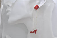 Close-up of glittery perspex leg earring with red stiletto shoe worn on model ear