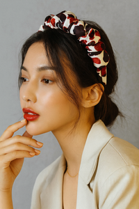 Model wearing ruffled red and black print headband styled with a low bun