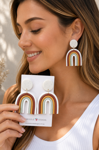 Close-up of clay rainbow drop earring worn on ear, showing arched stripe detail