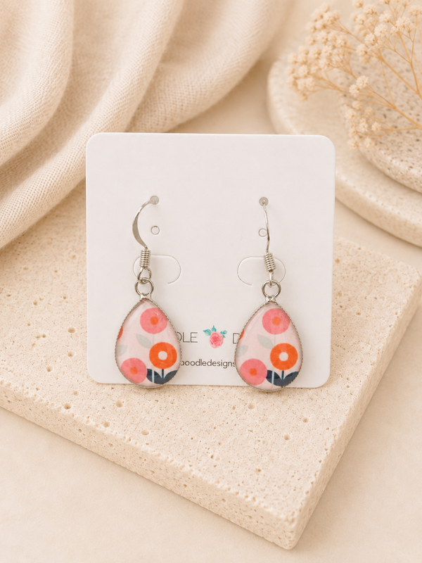 Teardrop dangle earrings with pink and orange retro floral print in silver-tone frames on card