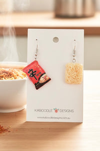 Resin Shin Ramyun earrings on Kaboodle card, one red noodle packet charm and one noodle block charm