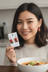 Woman wearing a single red Shin Ramyun packet earring while holding the earring card