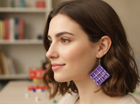 Purple tic tac toe earring worn on model's ear, side profile view