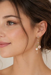Close-up of floral drop earring worn on ear showing rhinestone stud and layered blossom charms