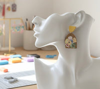 Close-up side view of floral resin earring worn on model's ear