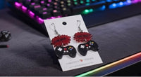 Close-up of Game Over drop earrings on dark keyboard, showing controller button detail