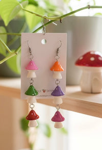 Three-tier mushroom resin drop earrings on card, hanging with pink, green and red toadstool charms