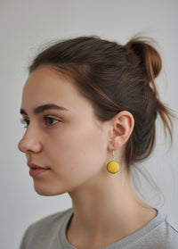 Close-up of a yellow burger earring with lettuce trim worn on a model's ear