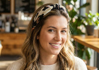 Woman wearing a cream, black and tan animal print knotted fabric headband in a cafe
