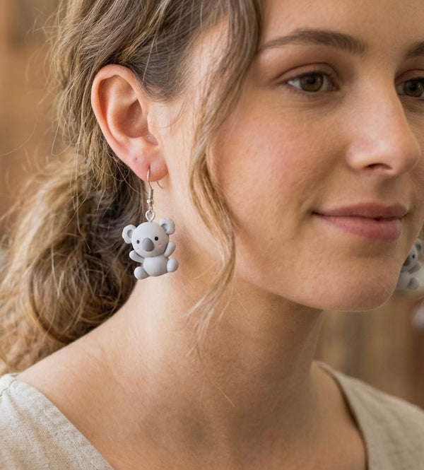 Close-up of a grey koala drop earring worn on a model's ear