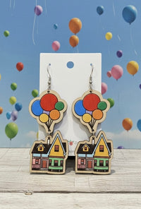 Wooden drop earrings shaped as a cottage lifted by colourful balloons, shown on card backing