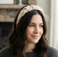 Cream ruffled fabric headband worn on a woman's head, front view
