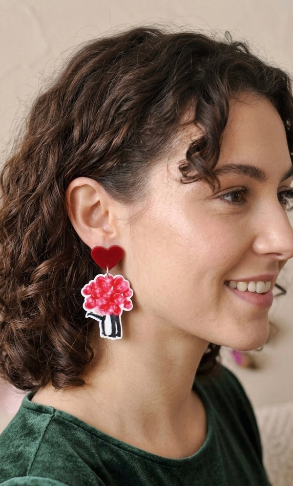 Red heart and rose bouquet perspex drop earring worn on model's ear, side view