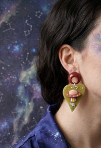 Alien UFO earring with cow and crescent moon detail worn on model's ear, close-up side view
