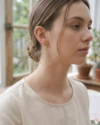 Close-up of model wearing gold moon and star drop earring, side profile view
