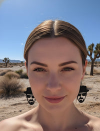 Close-up of woman wearing black Heisenberg cutout earrings, front-facing view