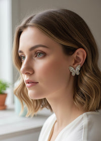 Close-up of gold rhinestone butterfly earring worn on a model's ear, shown in profile