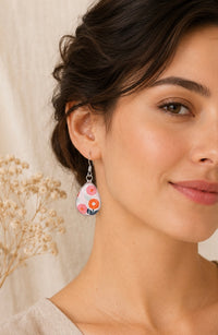 Close-up of teardrop earring worn on ear showing pink and orange floral design
