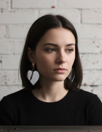 Close-up of model wearing mirror heart drop earring with lightning bolt stud