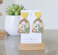 Mustard yellow arch drop earrings with tan floral panel on earring card