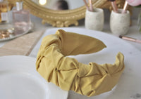 Close-up of mustard yellow ruffled fabric headband on a marble tray