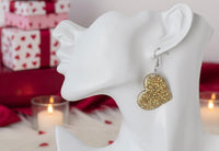Close-up side view of gold glitter heart earring worn on model's ear