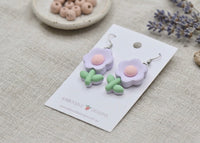 Pair of purple flower earrings laid flat on card showing leaf detail