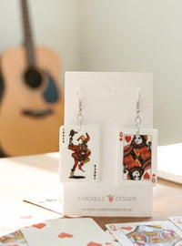 Joker and Queen of Hearts playing card drop earrings displayed on a white card