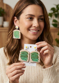 Close-up of avocado toast earring worn on ear, showing fried egg stud and layered avocado slice detail