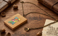Wooden pendant necklace laid flat showing chain, lobster clasp and illustrated design