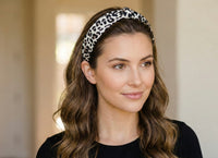 Woman wearing leopard print knotted headband over wavy brown hair, front view