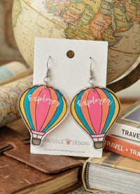 Pair of acrylic hot air balloon earrings with pink, orange, teal and yellow stripes reading 'explorer', on card backing