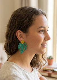 Monstera leaf glitter earring worn on model's ear, side profile view