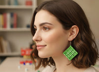 Woman wearing a green tic tac toe drop earring, side profile close-up