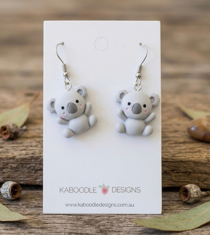 Pair of grey resin koala drop earrings on a white Kaboodle Designs card