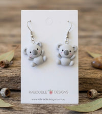 Pair of grey resin koala drop earrings on a white Kaboodle Designs card