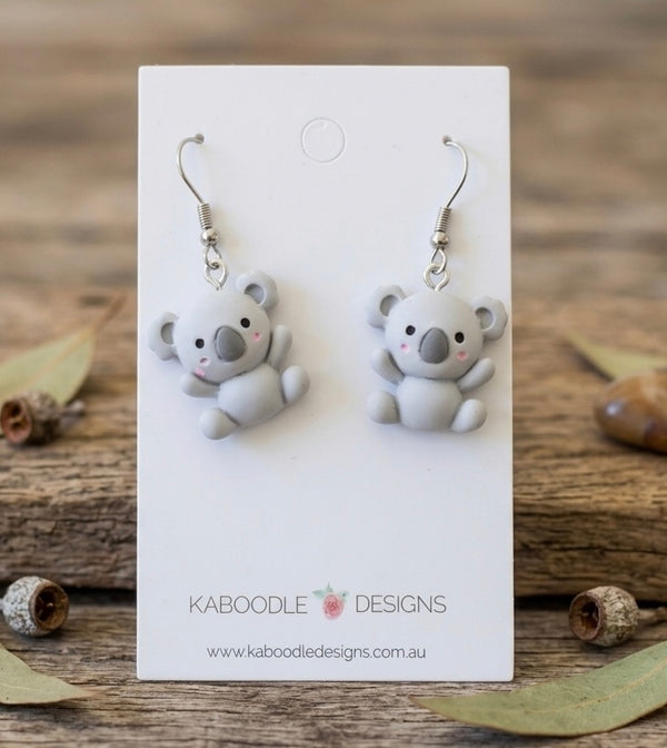 Pair of grey resin koala drop earrings on a white Kaboodle Designs card