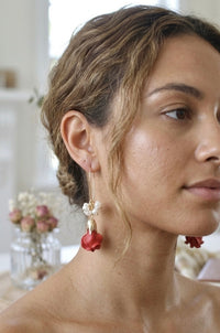 Model wearing red rose faux pearl earring shown close-up in profile